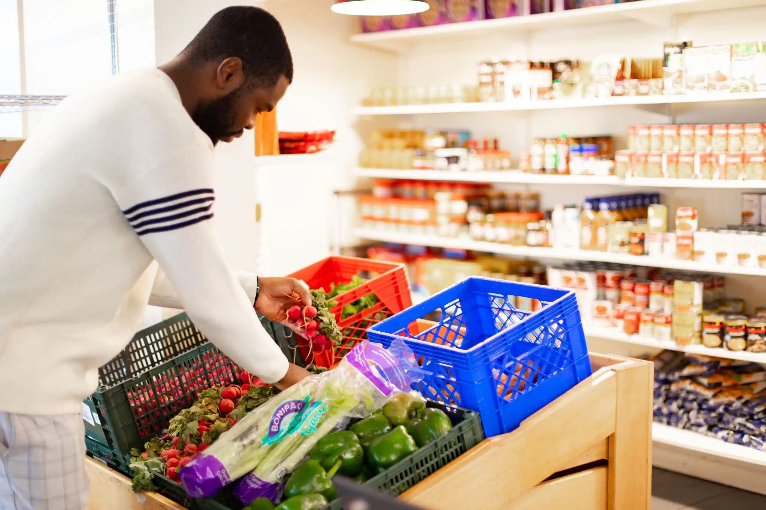 Bac_à_légumes Photo sur laquelle on voit Nathan qui choisi des légumes dans nos bacs à légumes pour un dépannage alimentaire au 66 rue Eddy
